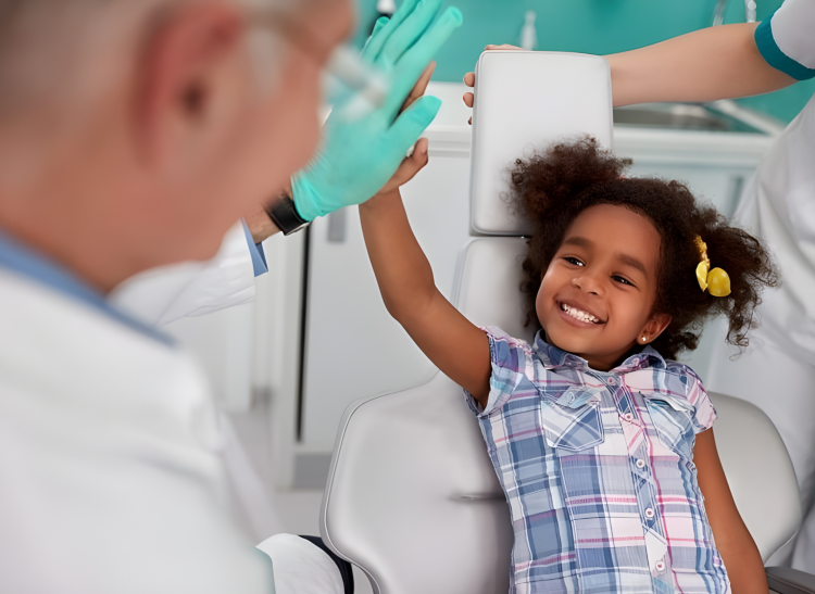 Pediatric dentist encouraging a child with a high-five during a comfortable dental visit